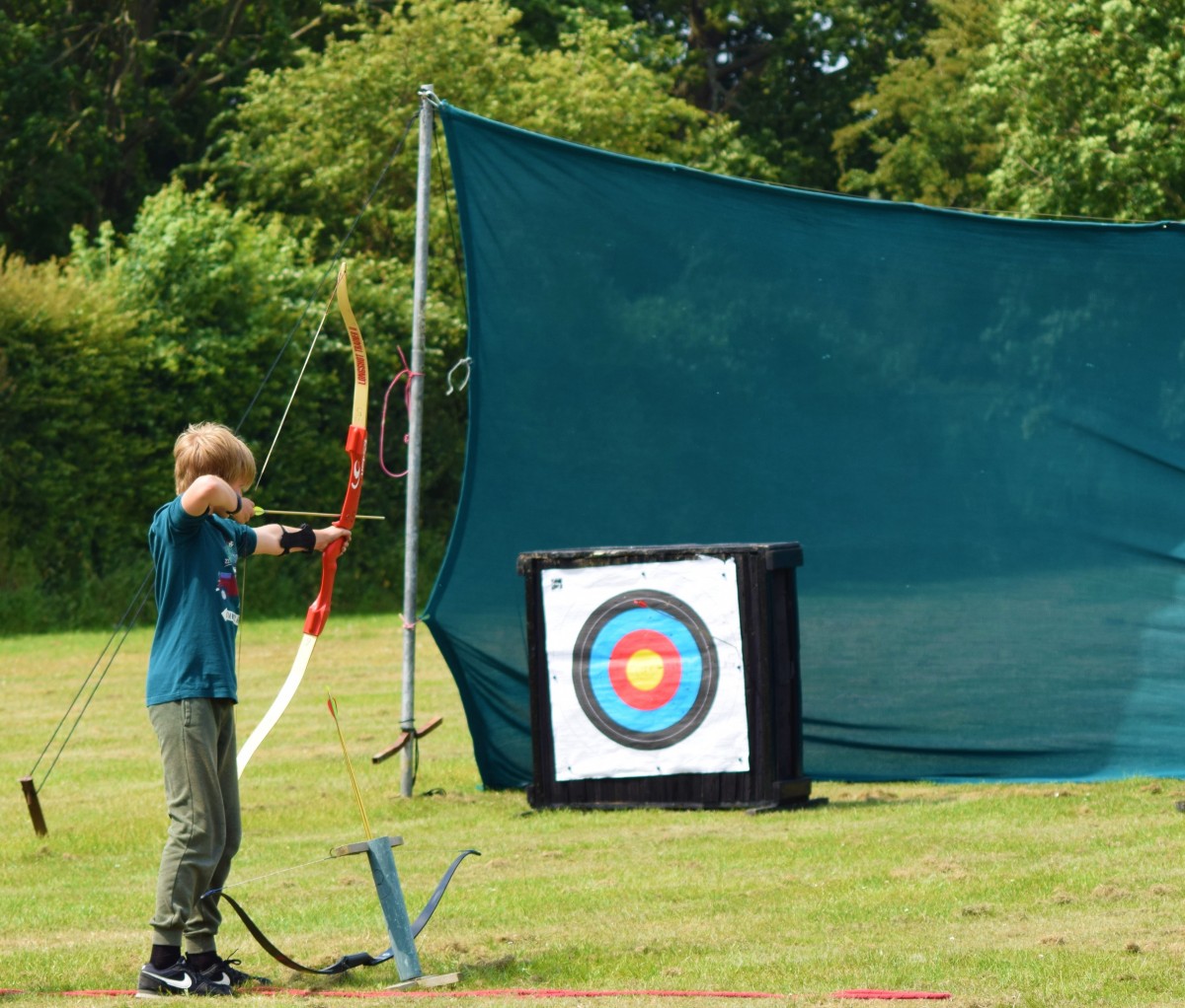 Child drawing bow and preparing to fire arrow at Archery field