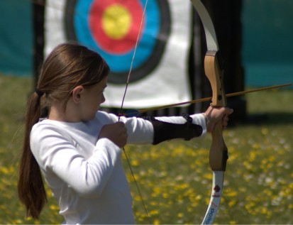 Girl drawing bow whilst playing Archery